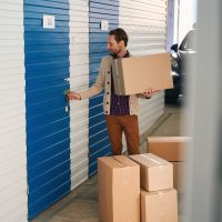 Young man with big cardboard boxes in self storage unit
